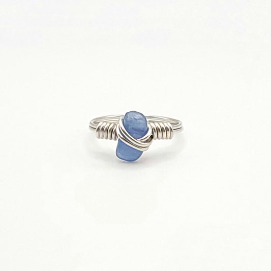 A handcrafted silver wire wrapped ring featuring a large blue kyanite stone in the center.