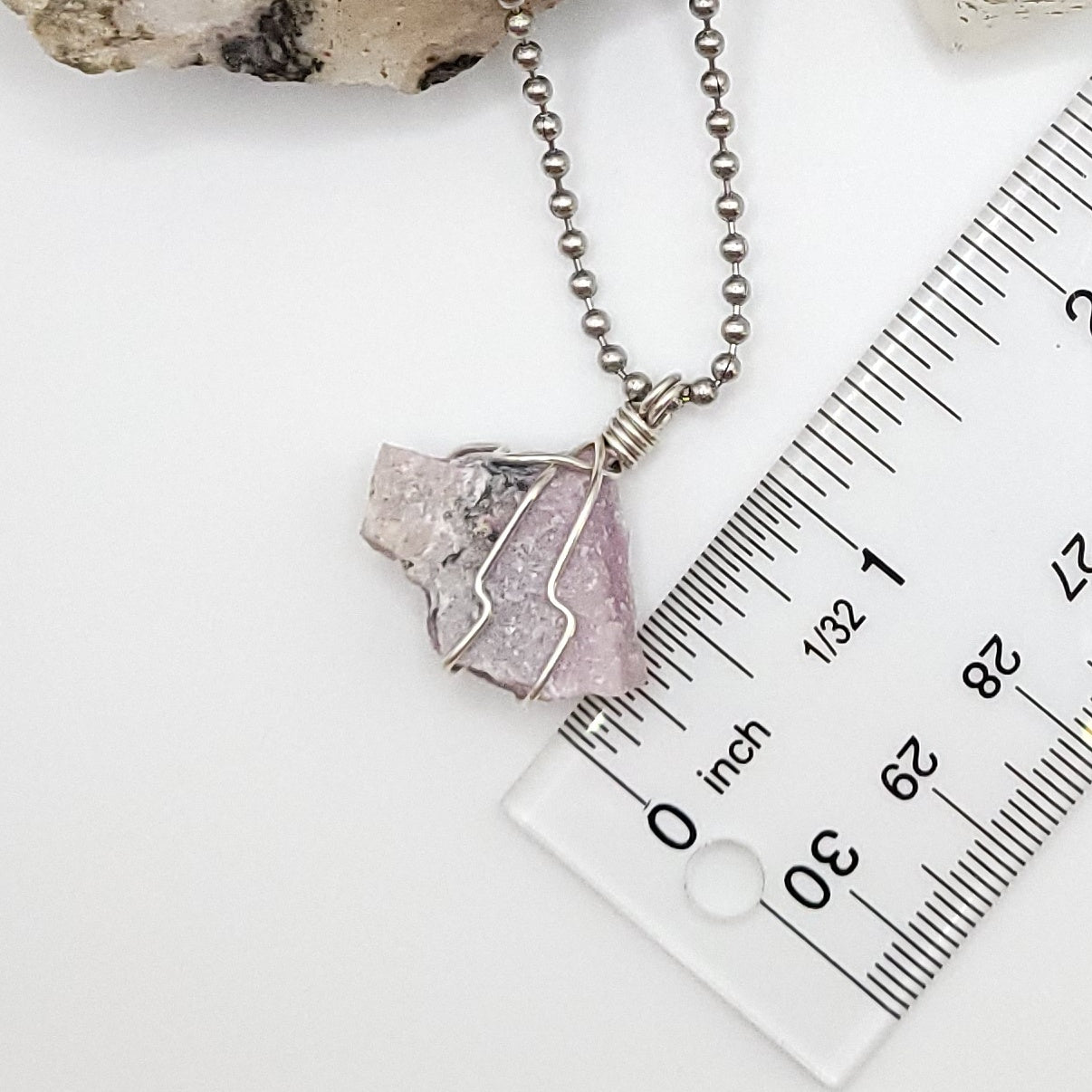 raw pink moonstone necklace in silver next to ruler, measuring about 1 inch