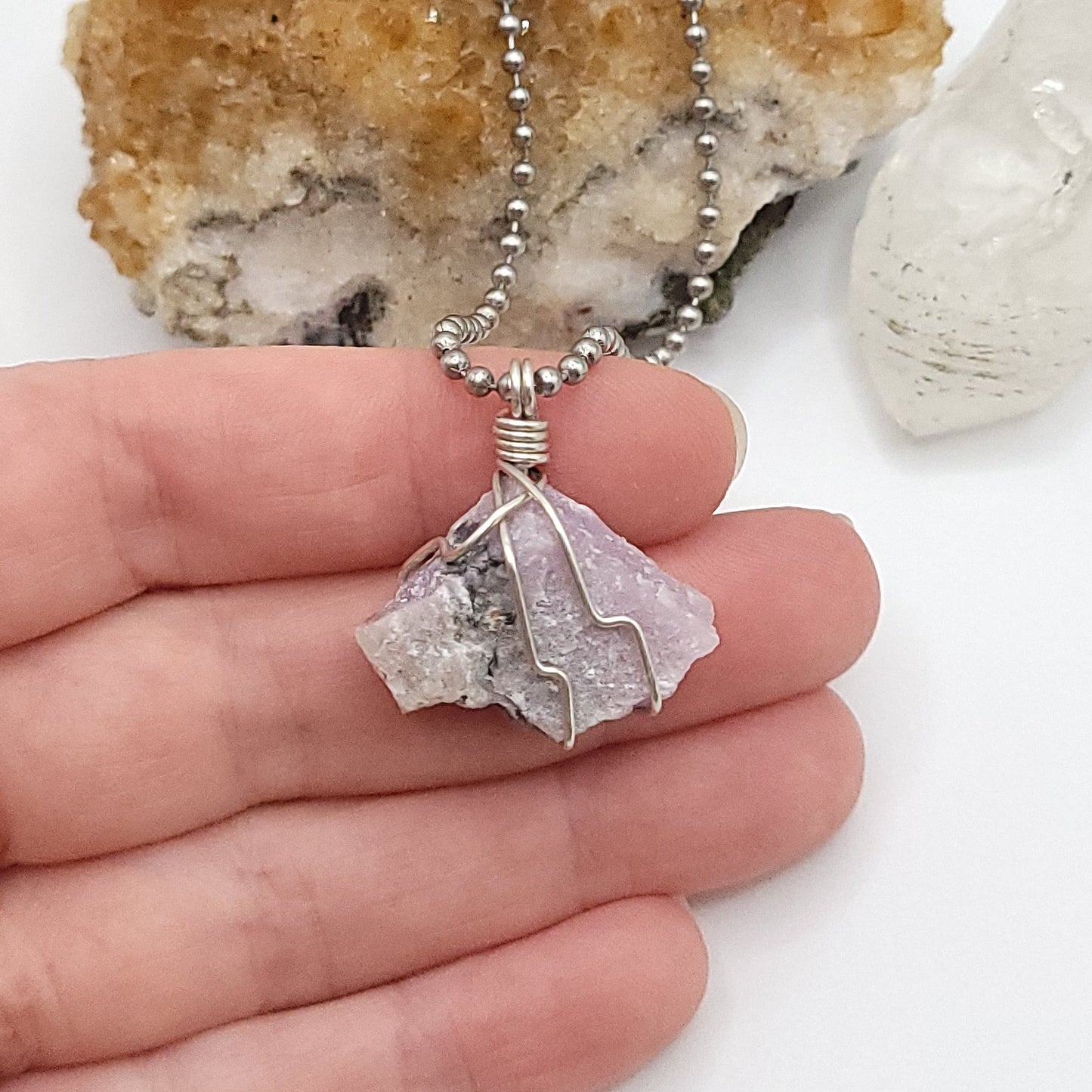 raw pink moonstone necklace in silver held in hand