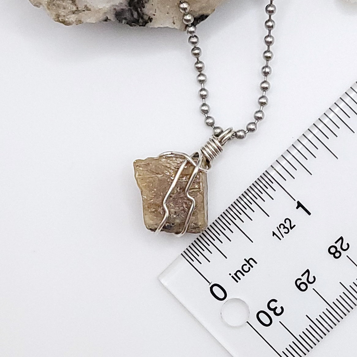 A honey yellow kyanite necklace wrapped in silver wire, suspended from a silver ball chain measurement about 1 inch