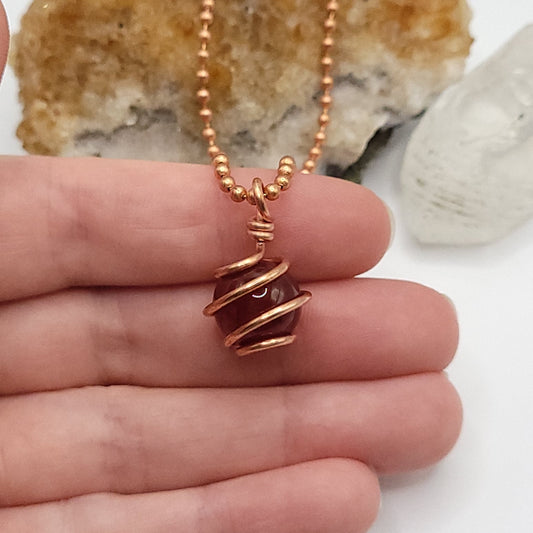 carnelian sphere necklace in copper wire in hand