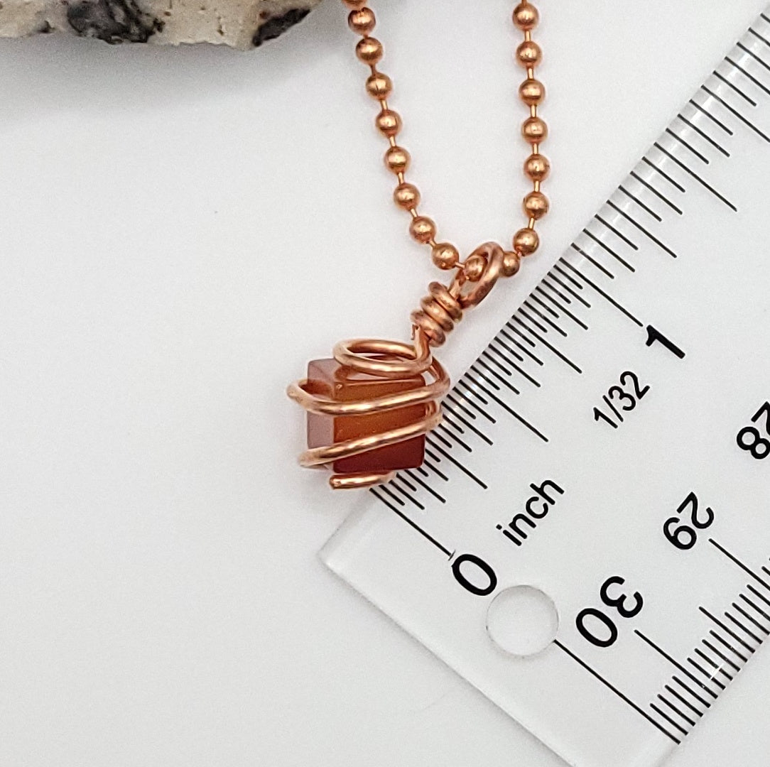 cube shaped carnelian necklace in copper next to ruler measuring about 1 inch