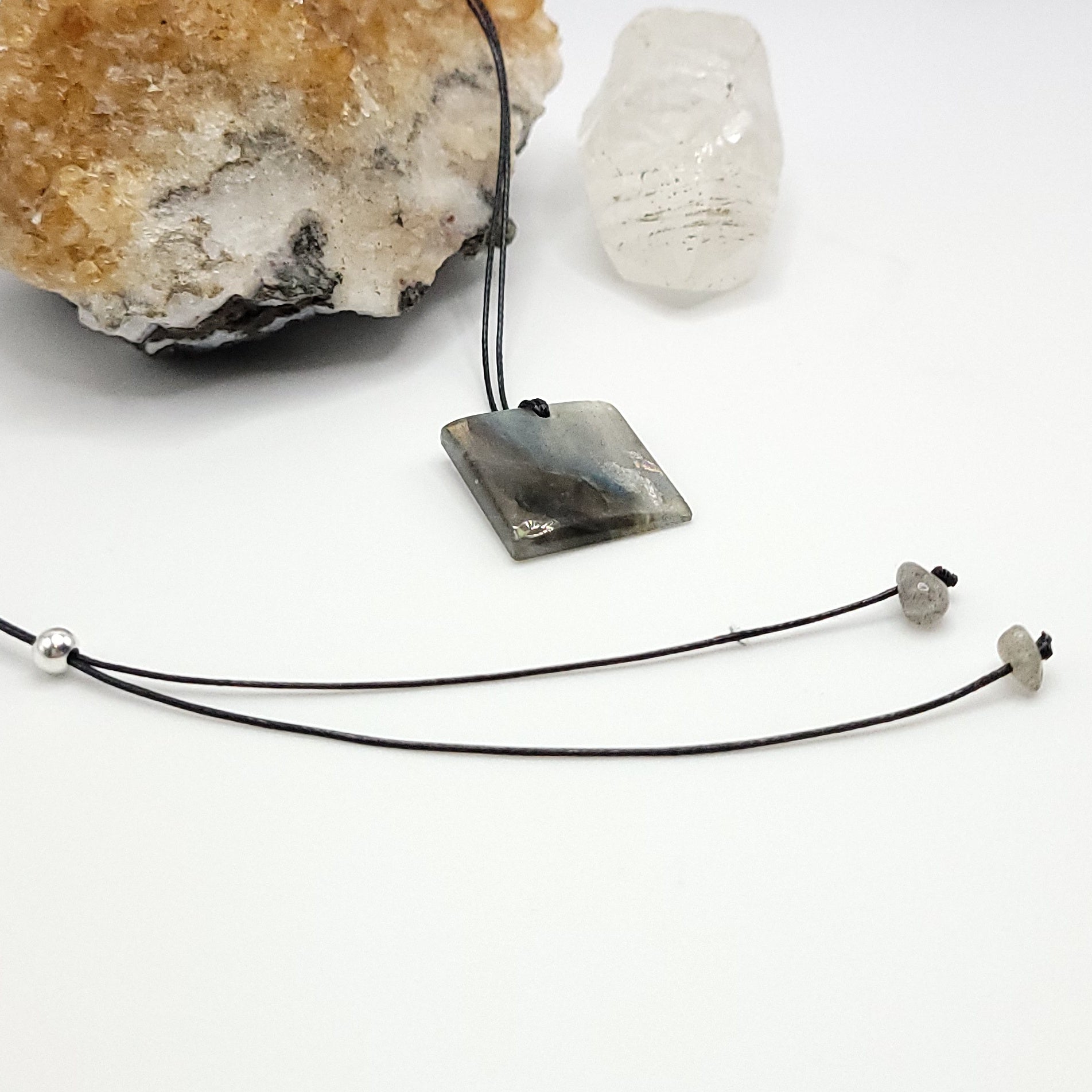 An adjustable Labradorite crystal necklace with a black waxed cotton cord, a sterling silver sliding bead, and two additional beads on the opposite end.