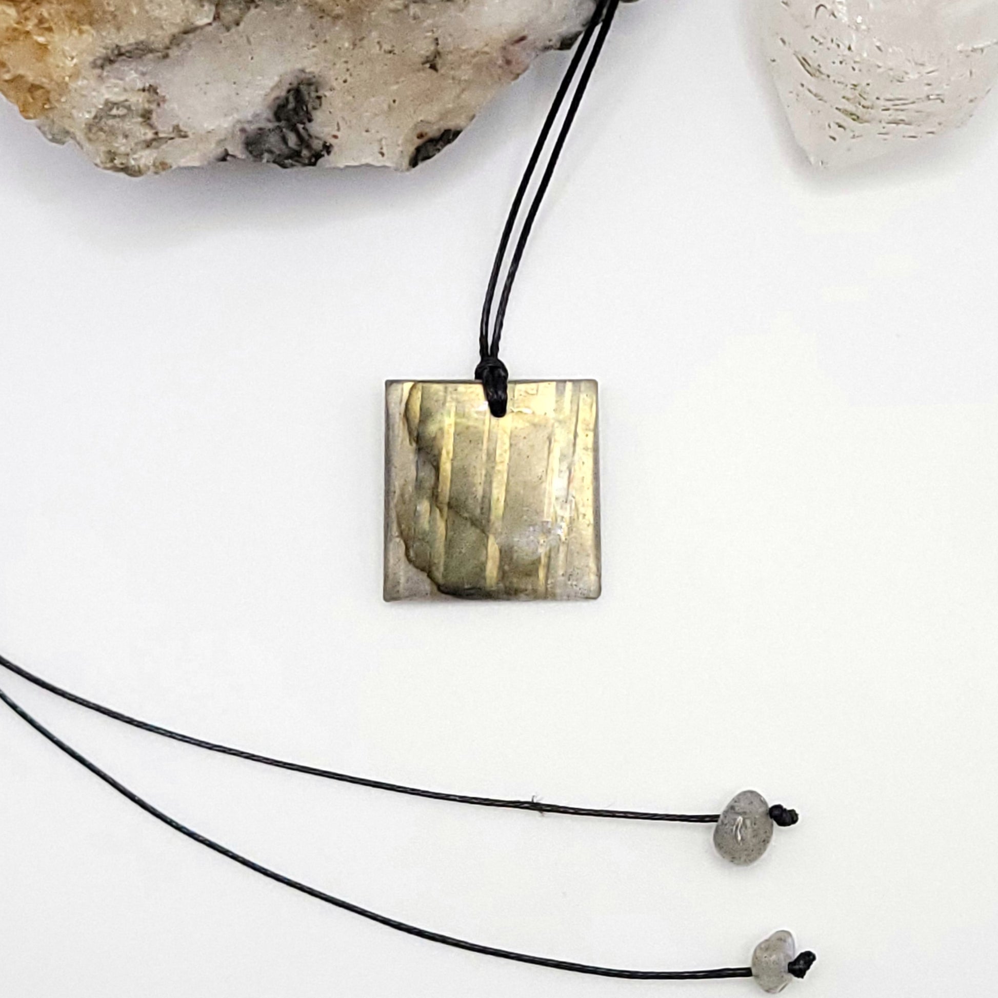 An adjustable Labradorite crystal necklace with a black waxed cotton cord, a sterling silver sliding bead, and two additional beads on the opposite end.