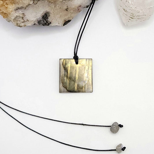 An adjustable Labradorite crystal necklace with a black waxed cotton cord, a sterling silver sliding bead, and two additional beads on the opposite end.