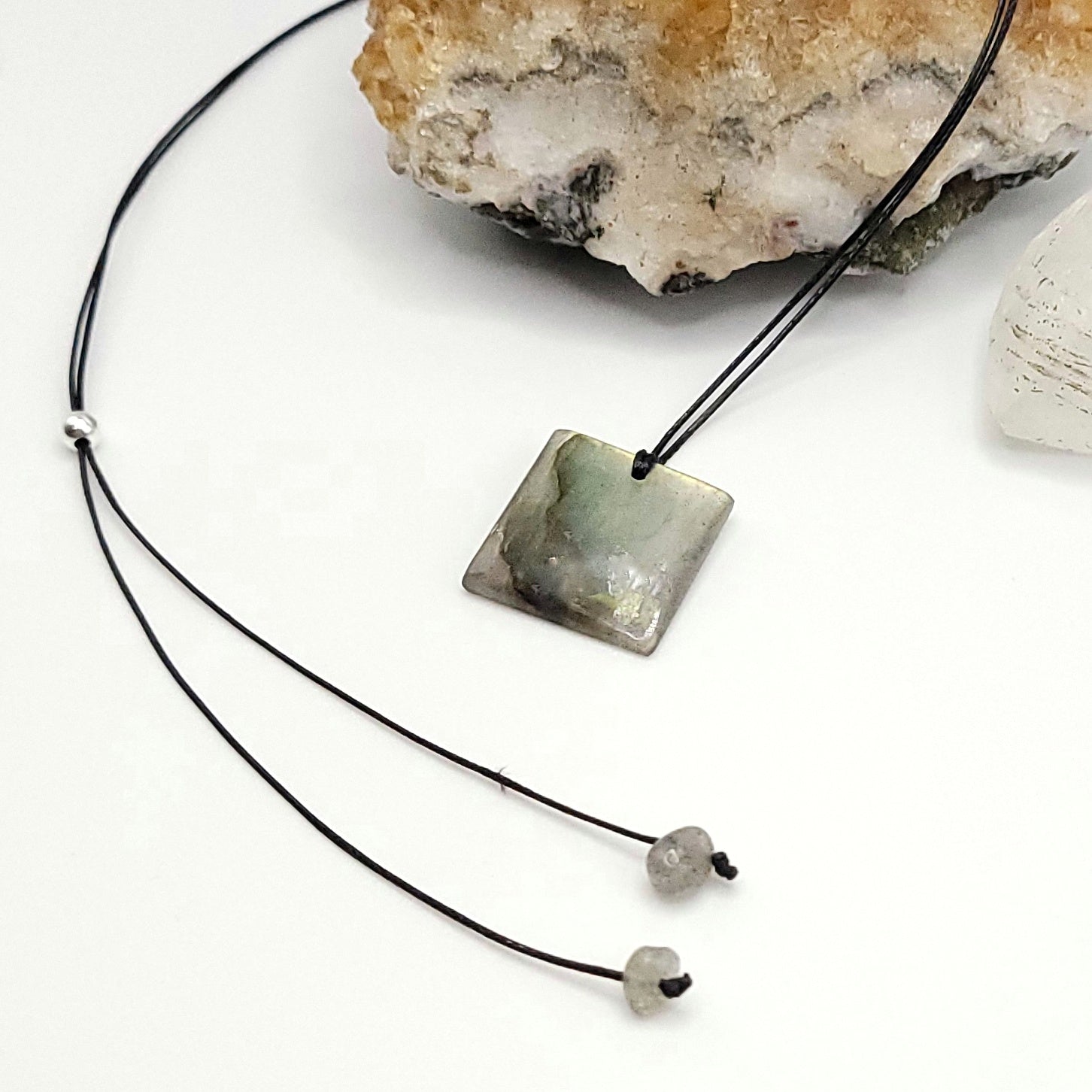An adjustable Labradorite crystal necklace with a black waxed cotton cord, a sterling silver sliding bead, and two additional beads on the opposite end - side view