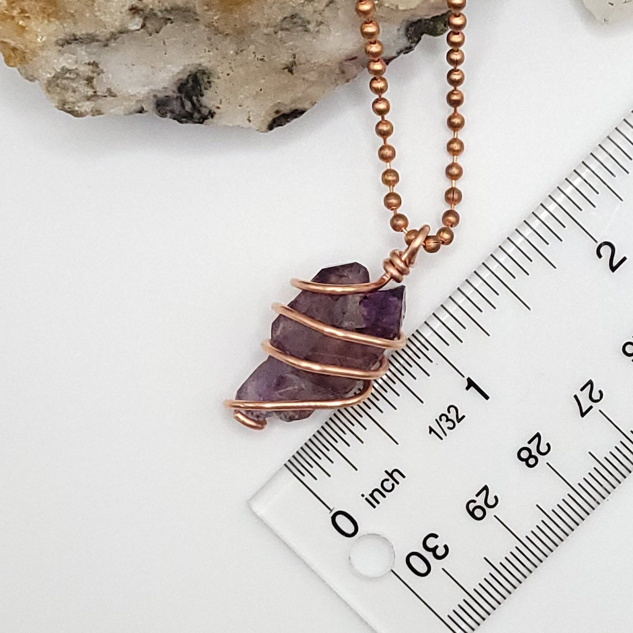 raw amethyst necklace in copper next to ruler
