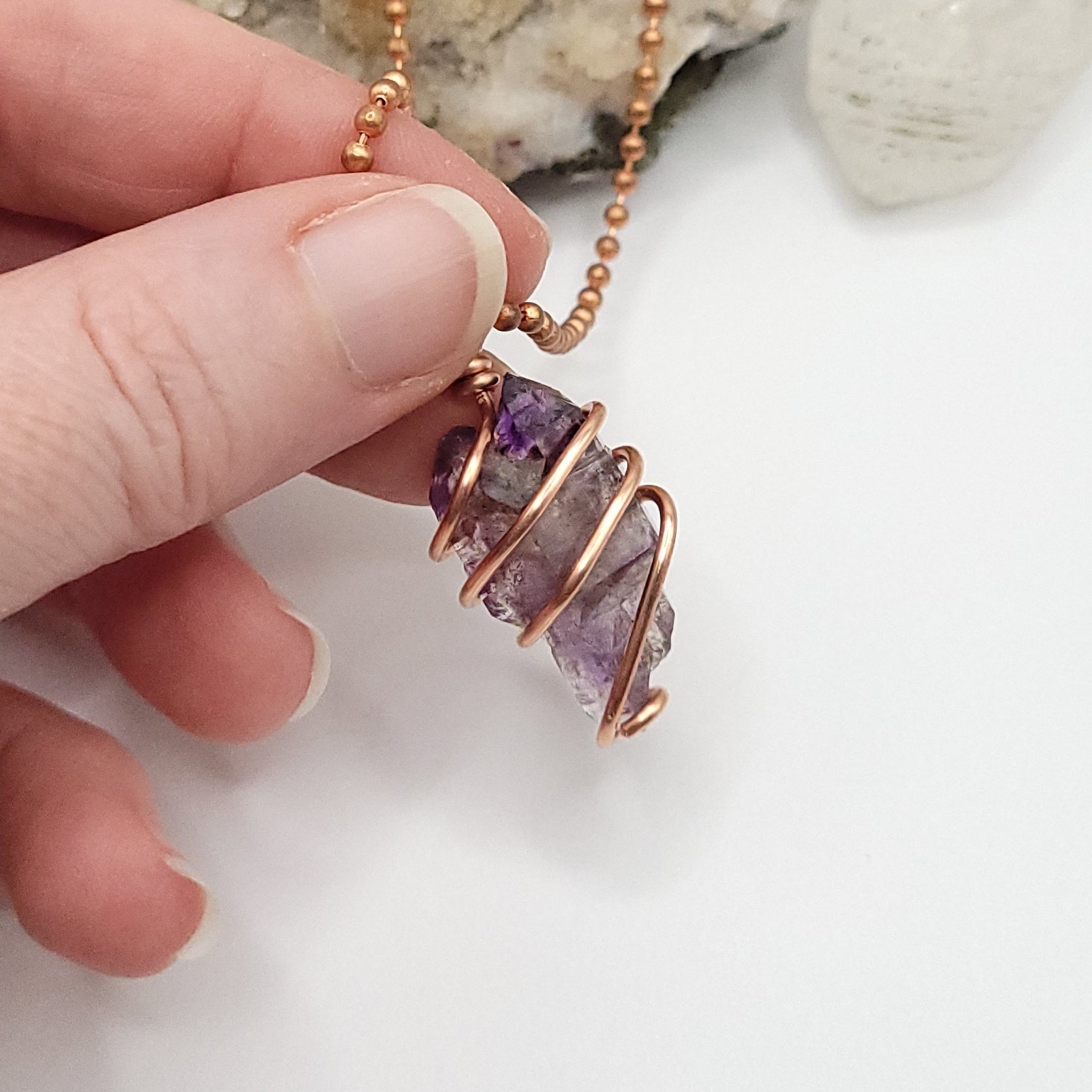 raw amethyst necklace in copper being held