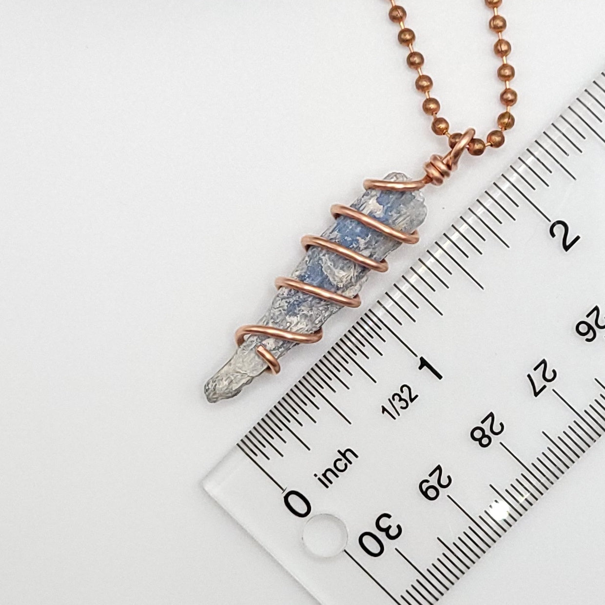 raw blue kyanite necklace in copper next to ruler measuring about 2 inches