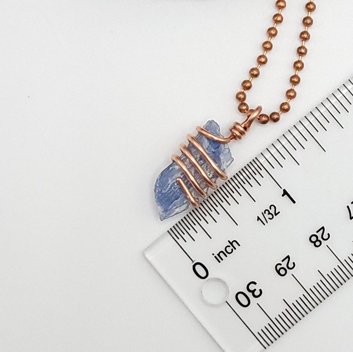 A raw Blue Kyanite crystal wrapped in copper wire, with a copper ball chain for a necklace measurement about 1.25 inches