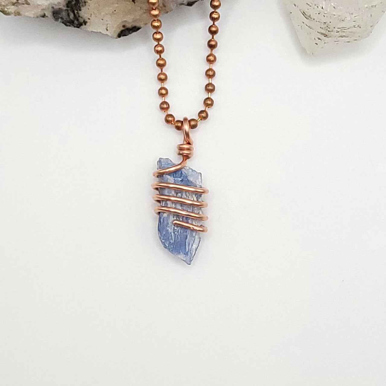 A raw Blue Kyanite crystal wrapped in copper wire, with a copper ball chain for a necklace.