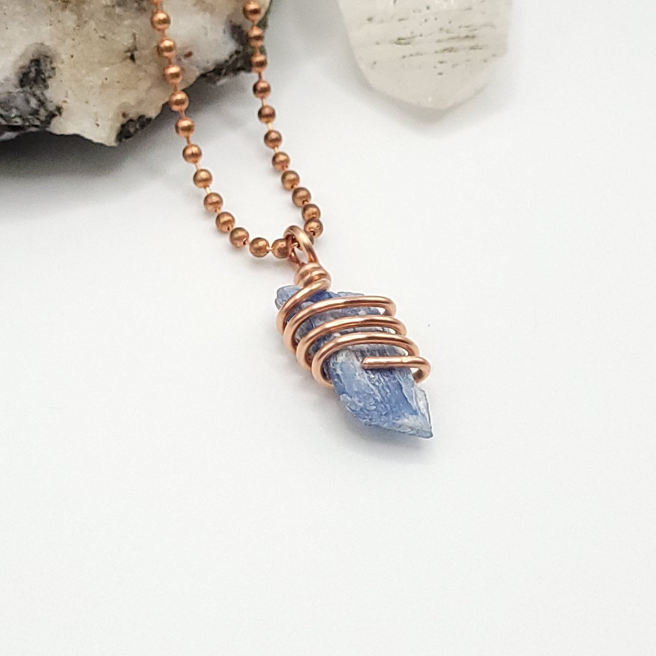 A raw Blue Kyanite crystal wrapped in copper wire, with a copper ball chain for a necklace side view