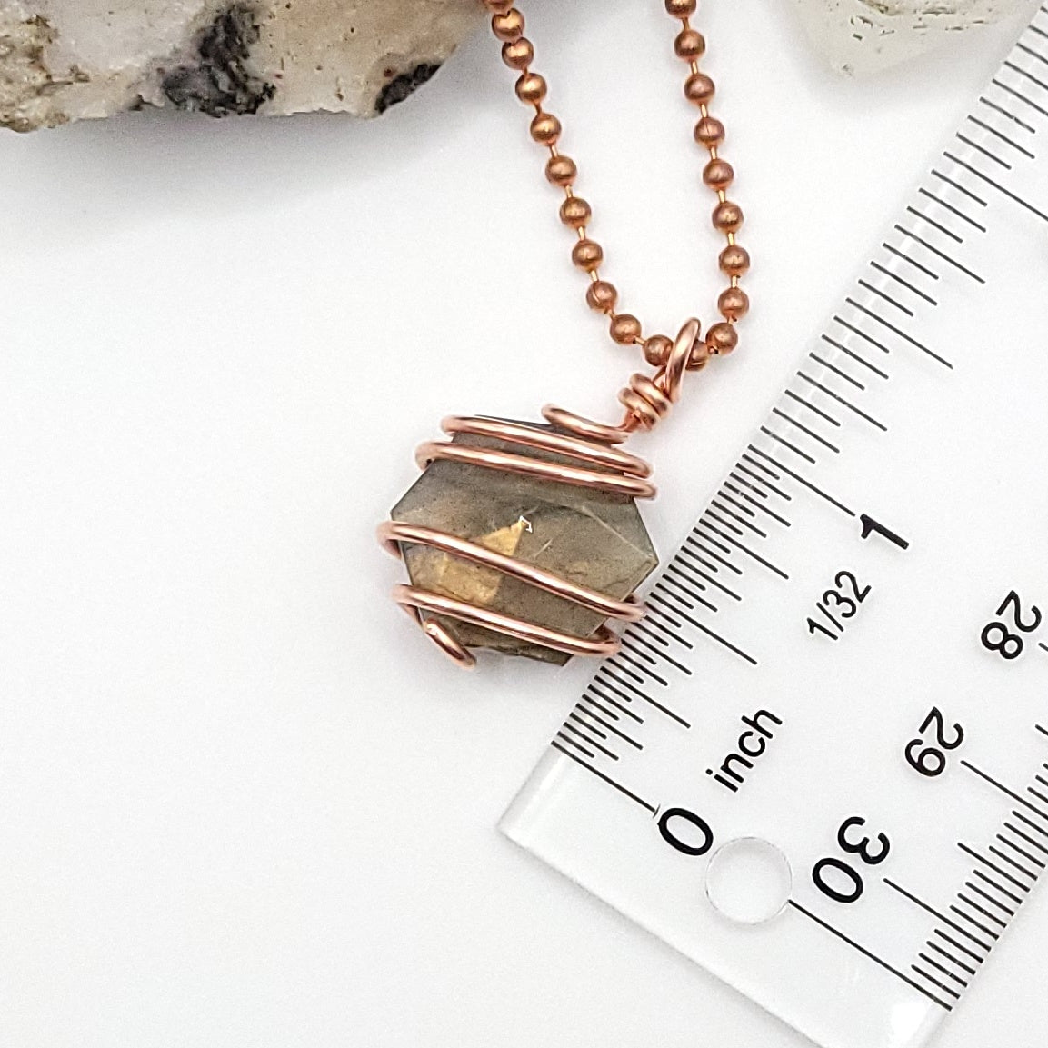 hexagon labradorite necklace in copper next to ruler, measuring about 1.25 inch