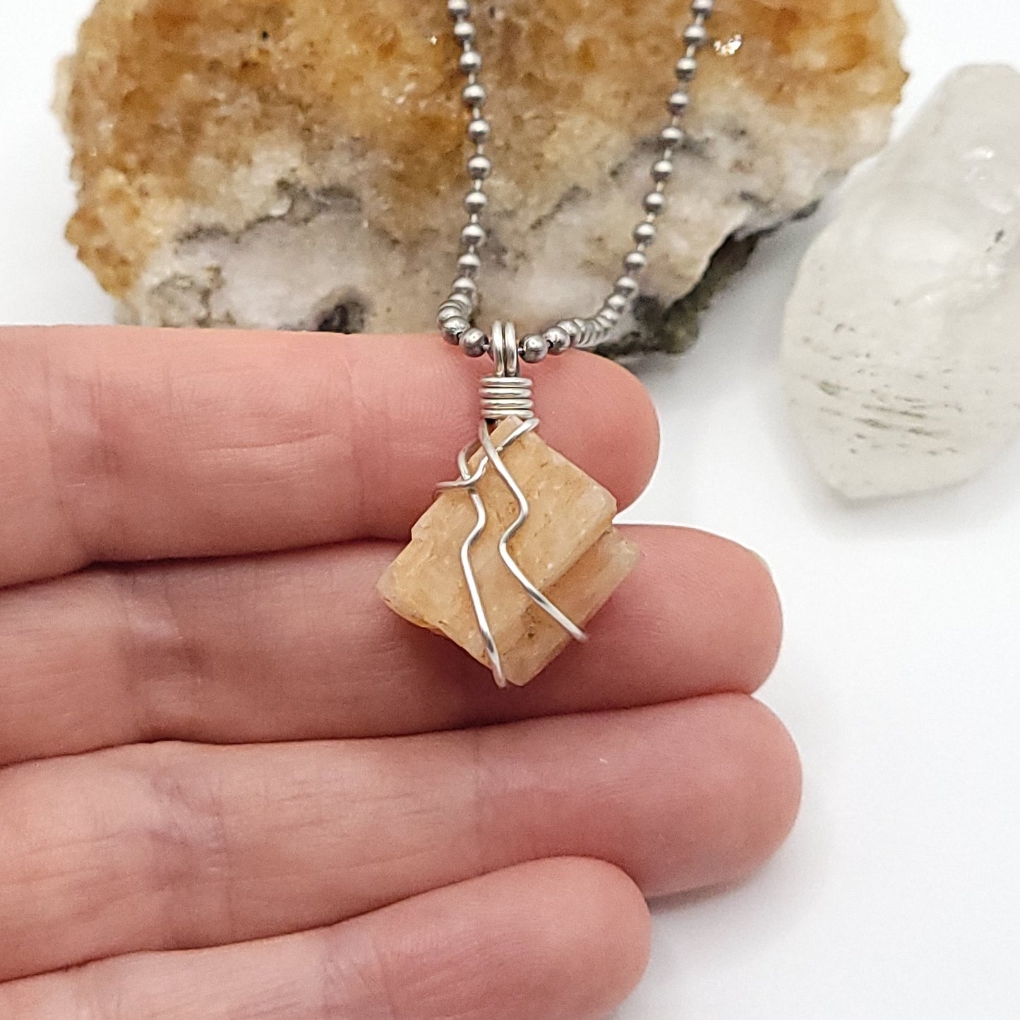 raw peach moonstone necklace in silver wire in hand