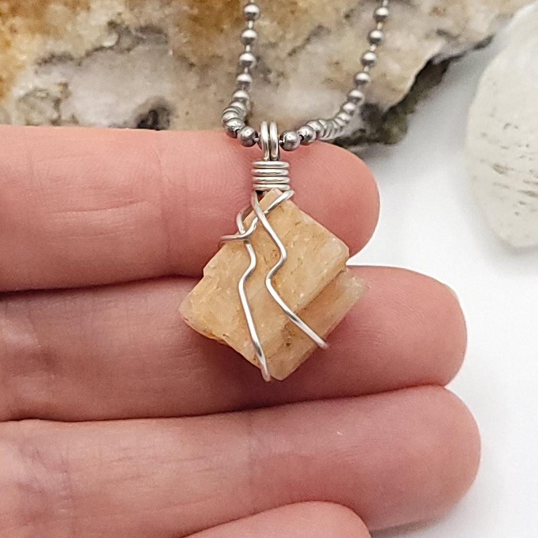 raw peach moonstone necklace in silver wire in hand close up