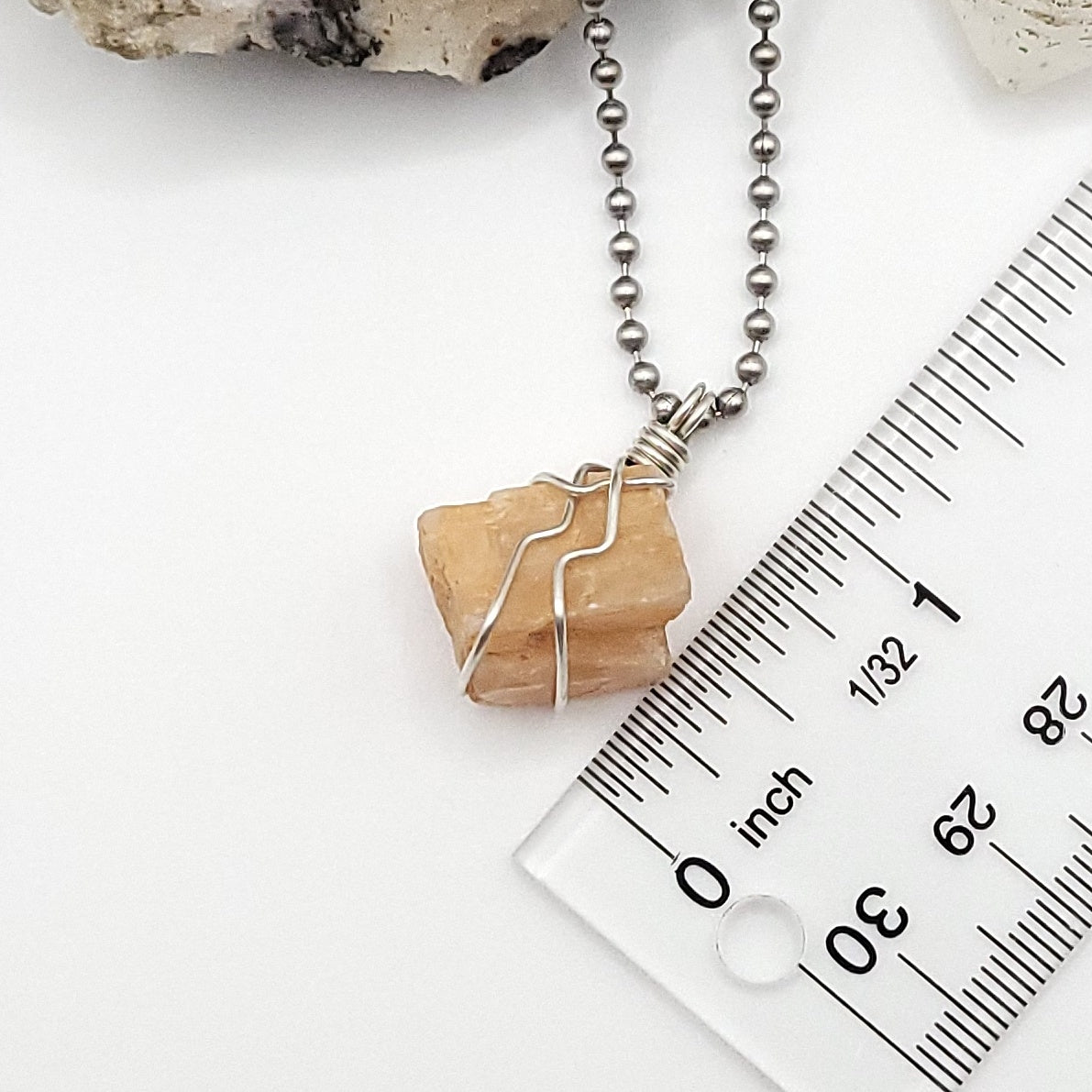 raw peach moonstone necklace in silver next to rule measuring about 1 inch