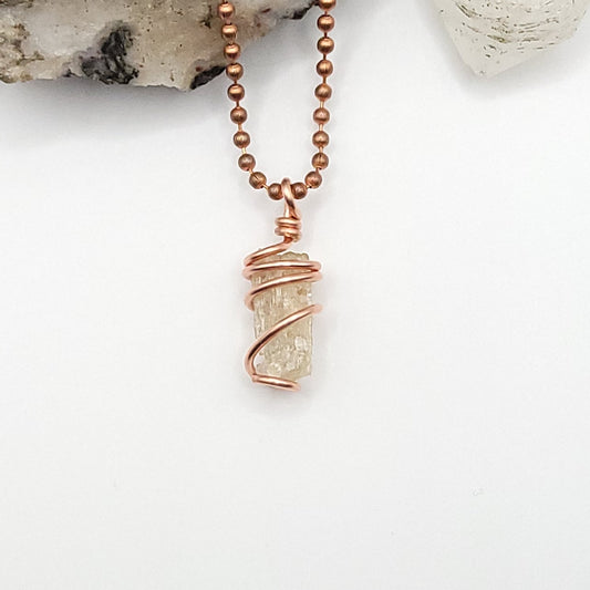 A raw golden Scapolite crystal necklace wrapped in pure copper wire, displayed on a white background.