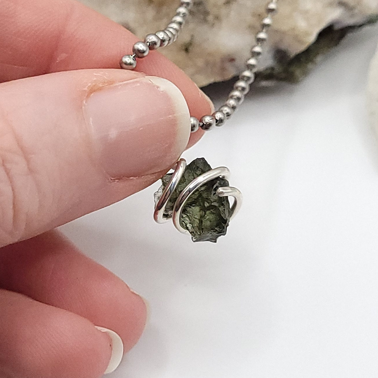 Raw Moldavite Crystal Necklace in Silver, lighted background