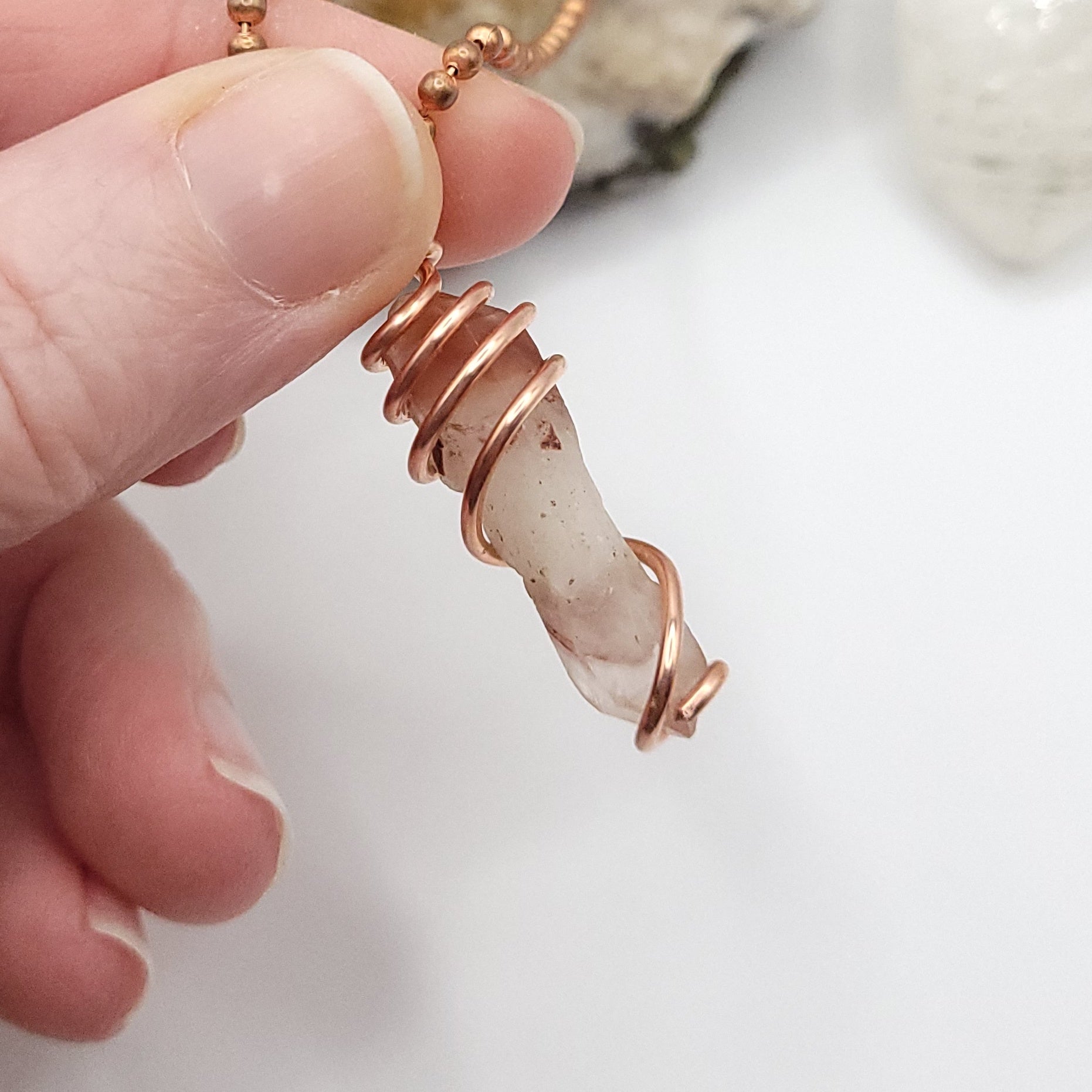 Red Fire Quartz Crystal Necklace in Copper Wire, against light on white background