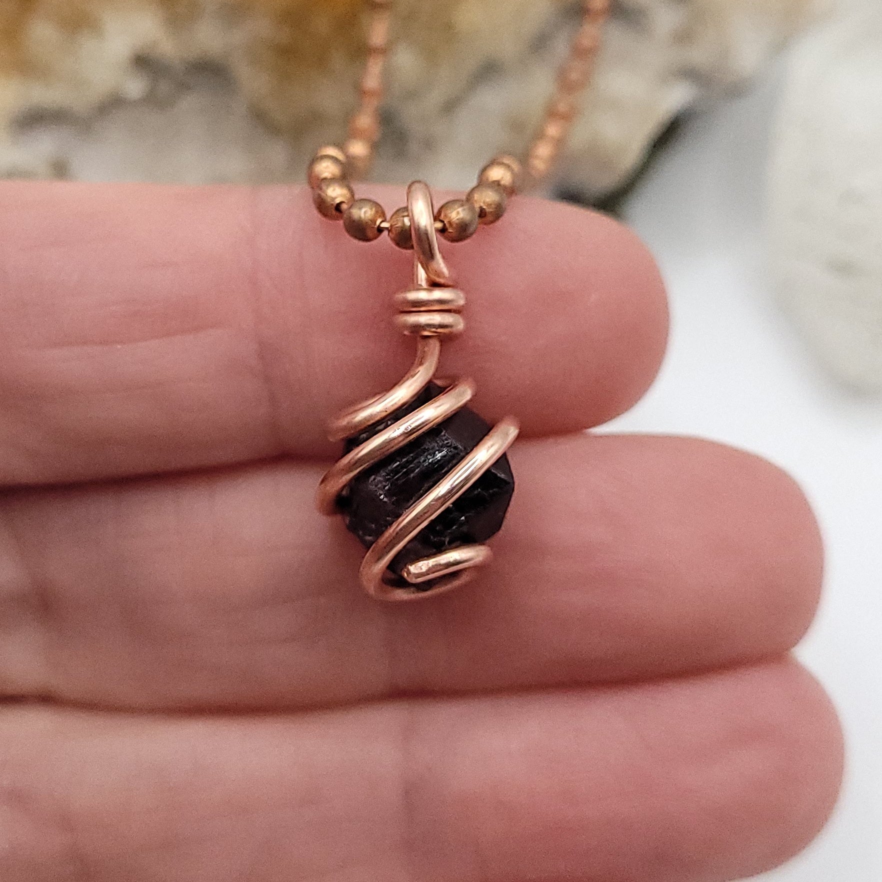 raw garnet in copper wire up close in hand
