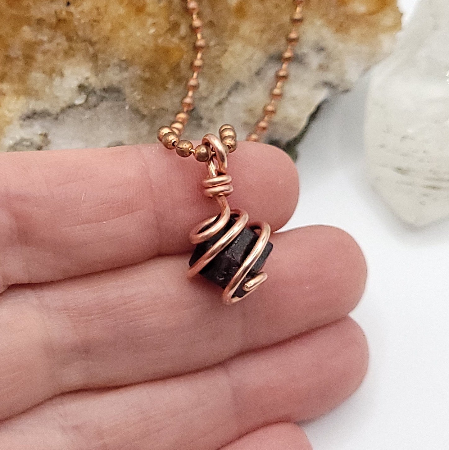 raw garnet necklace in copper in hand side view