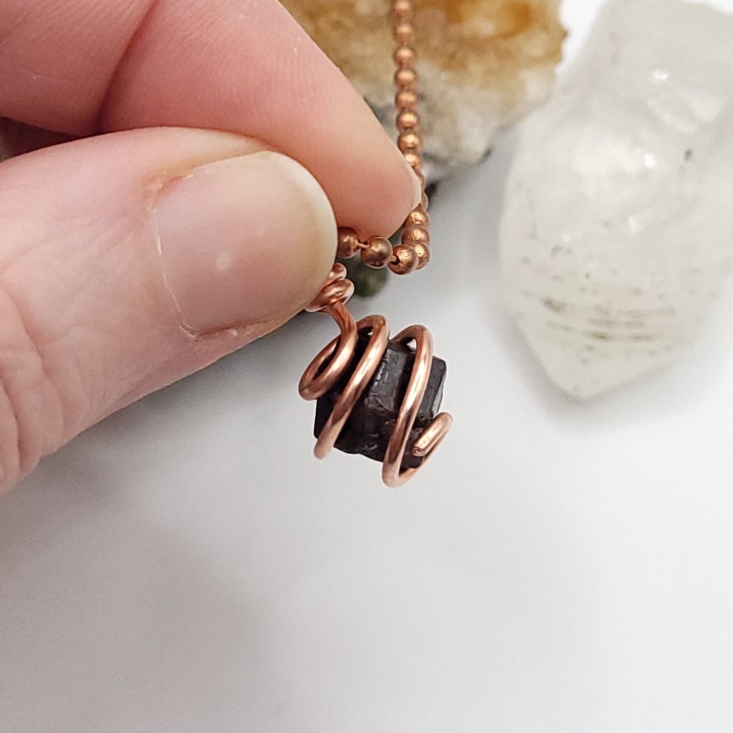 raw garnet necklace in copper in hand
