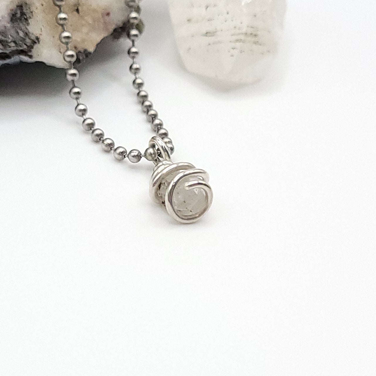 Raw Phenakite Crystal Necklace in silver, side view against white background