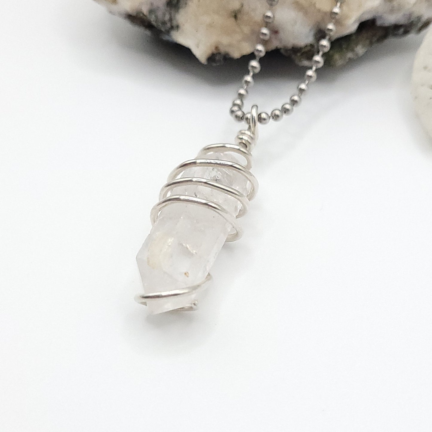 clear quartz necklace in silver side view on white background