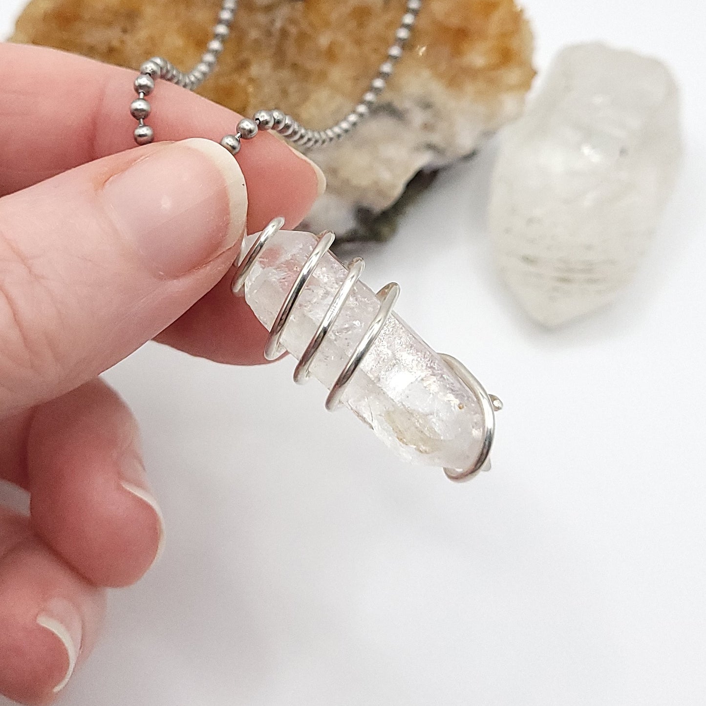clear quartz necklace in silver being held in hand