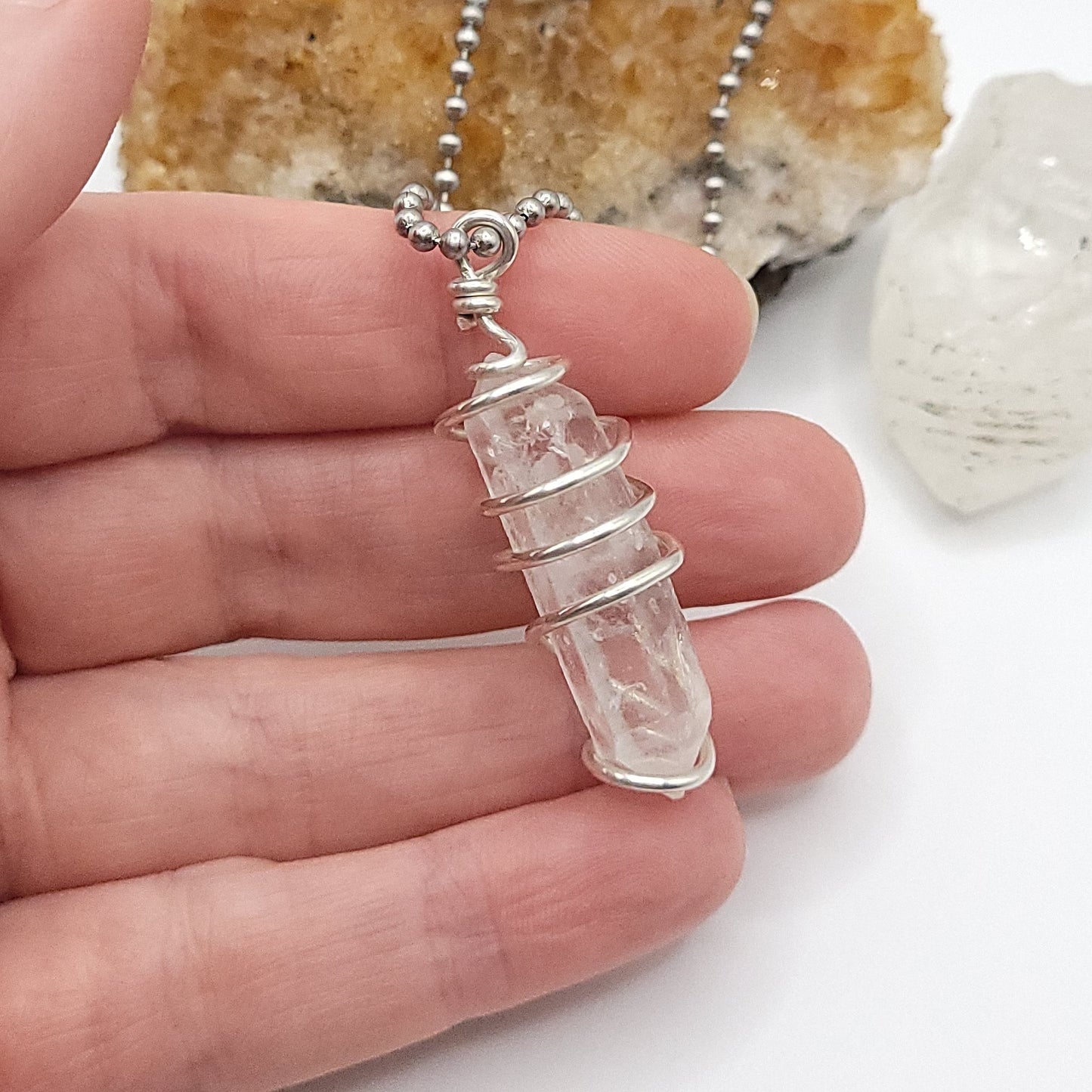 clear quartz necklace in silver side view in hand