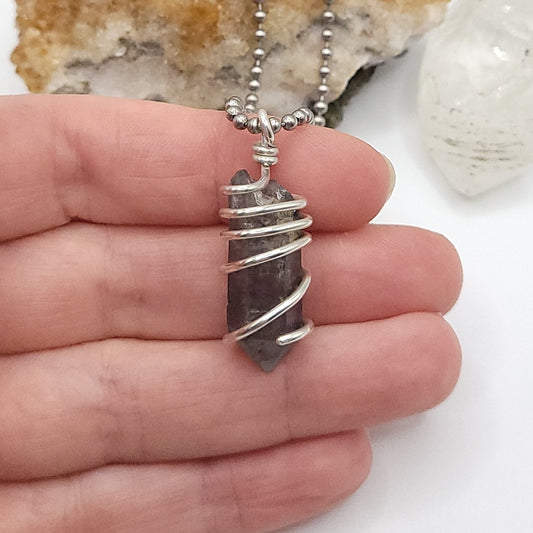 Tibetan Quartz Necklace in Silver held in hand, showcasing raw crystal wrapped in sterling silver.