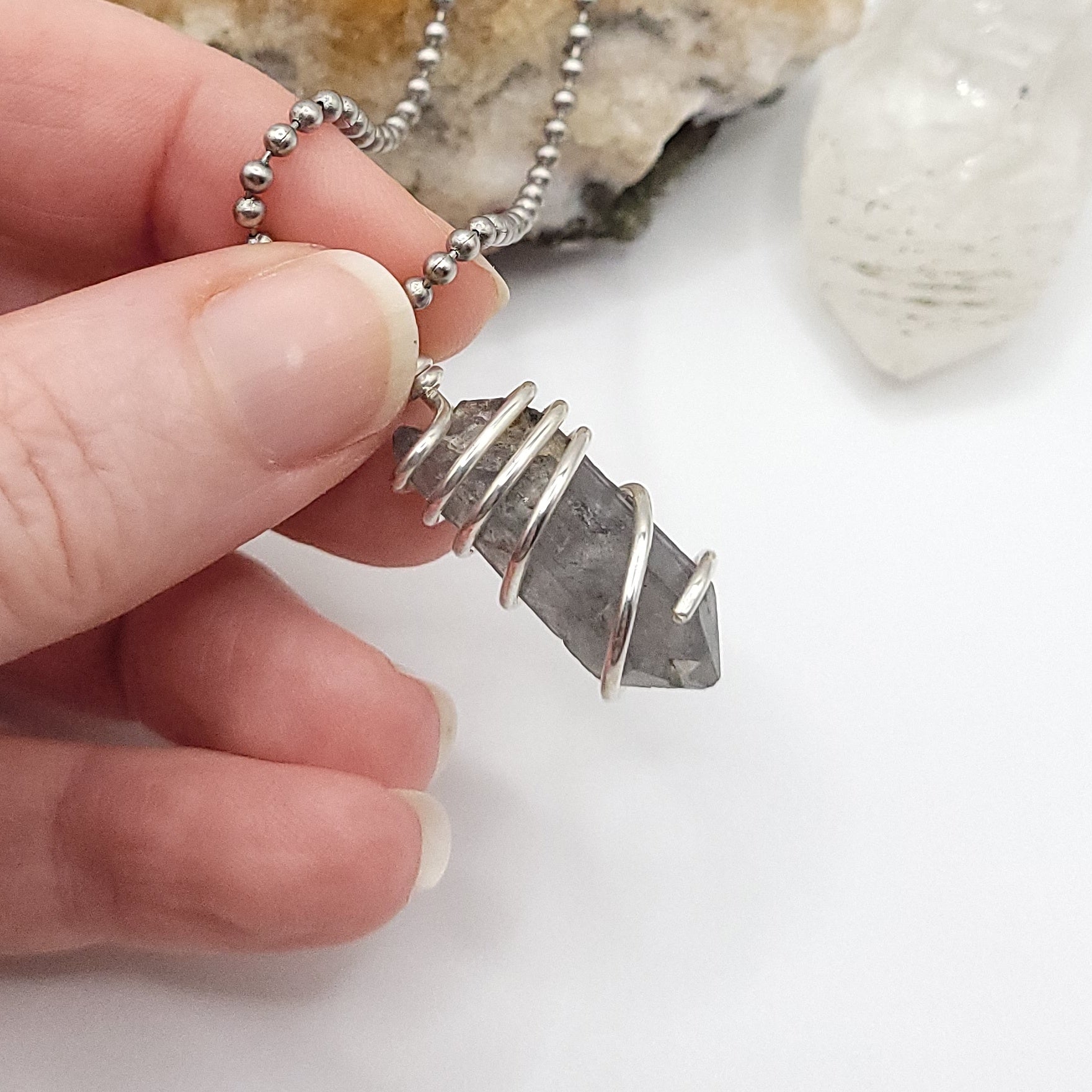 Tibetan Quartz Necklace in Silver held by hand, showcasing raw crystal wrapped in sterling silver wire.