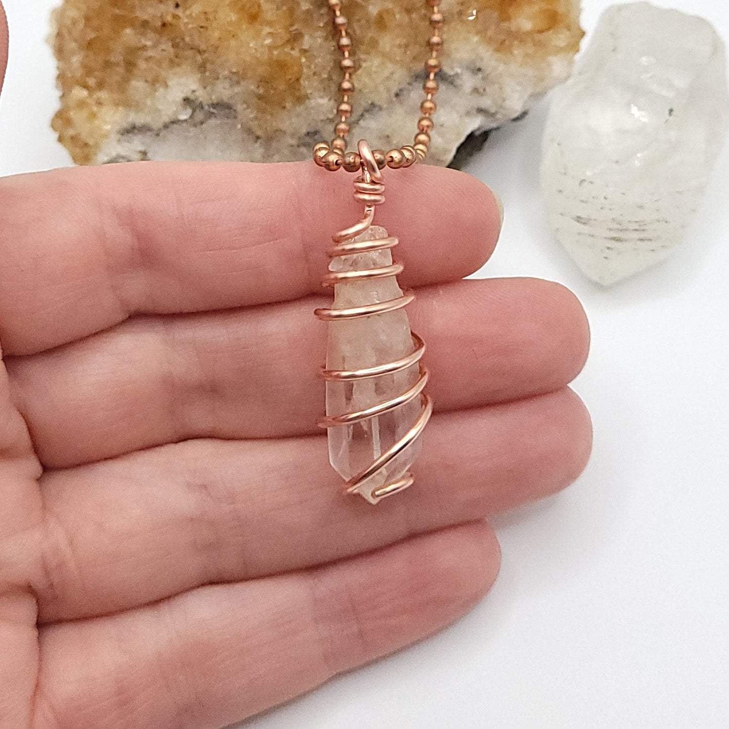 clear quartz necklace in copper in hand
