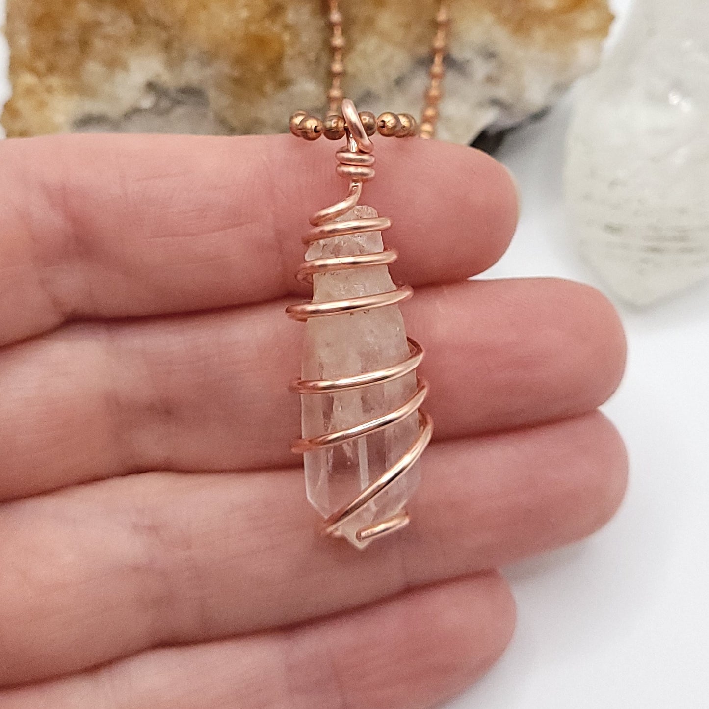 clear quartz necklace in copper in hand close up