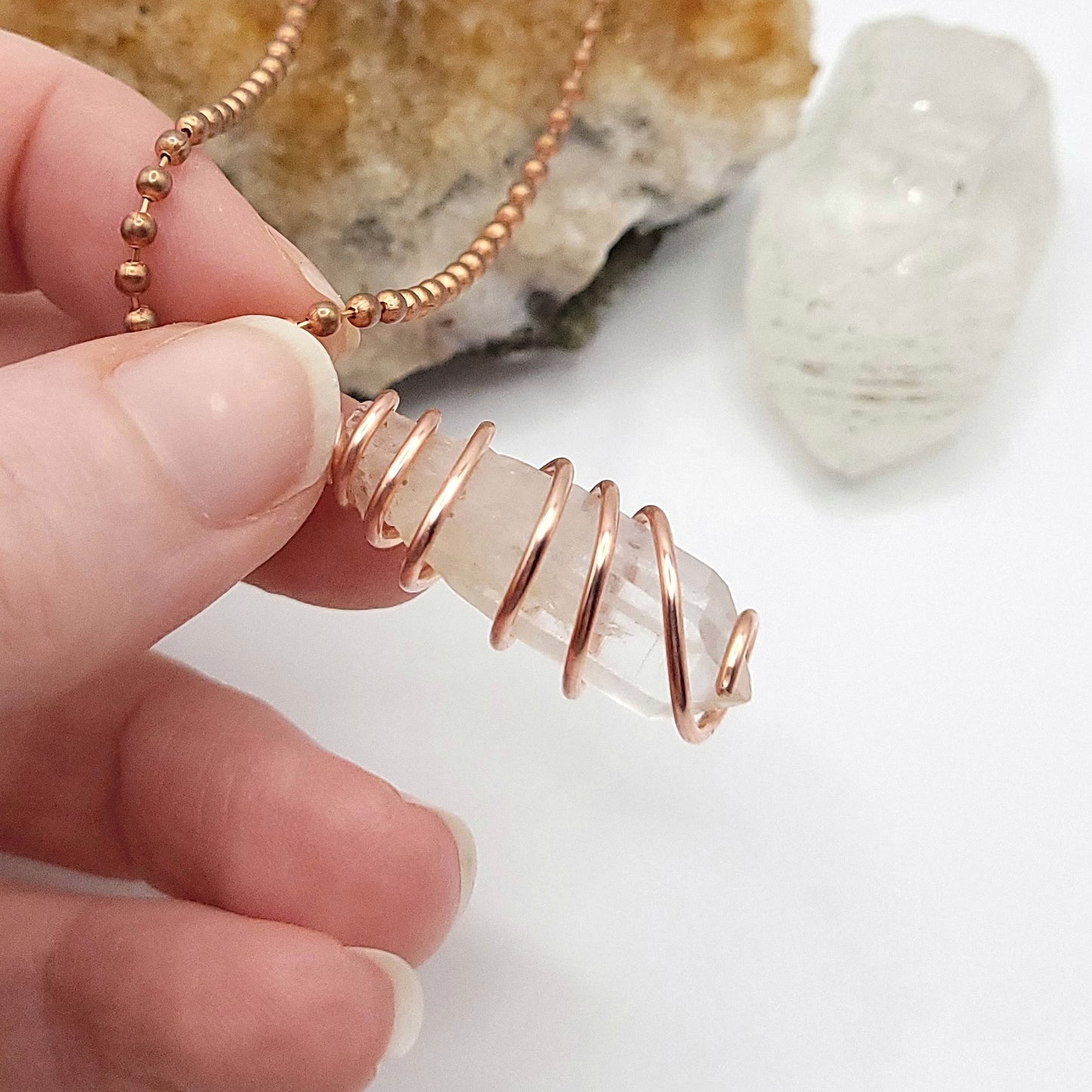 clear quartz necklace in copper side view in hand