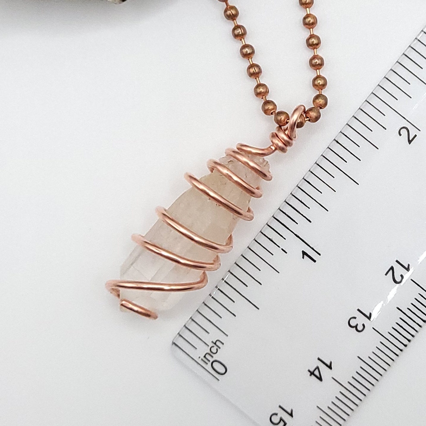clear quartz necklace in copper measurement next to ruler