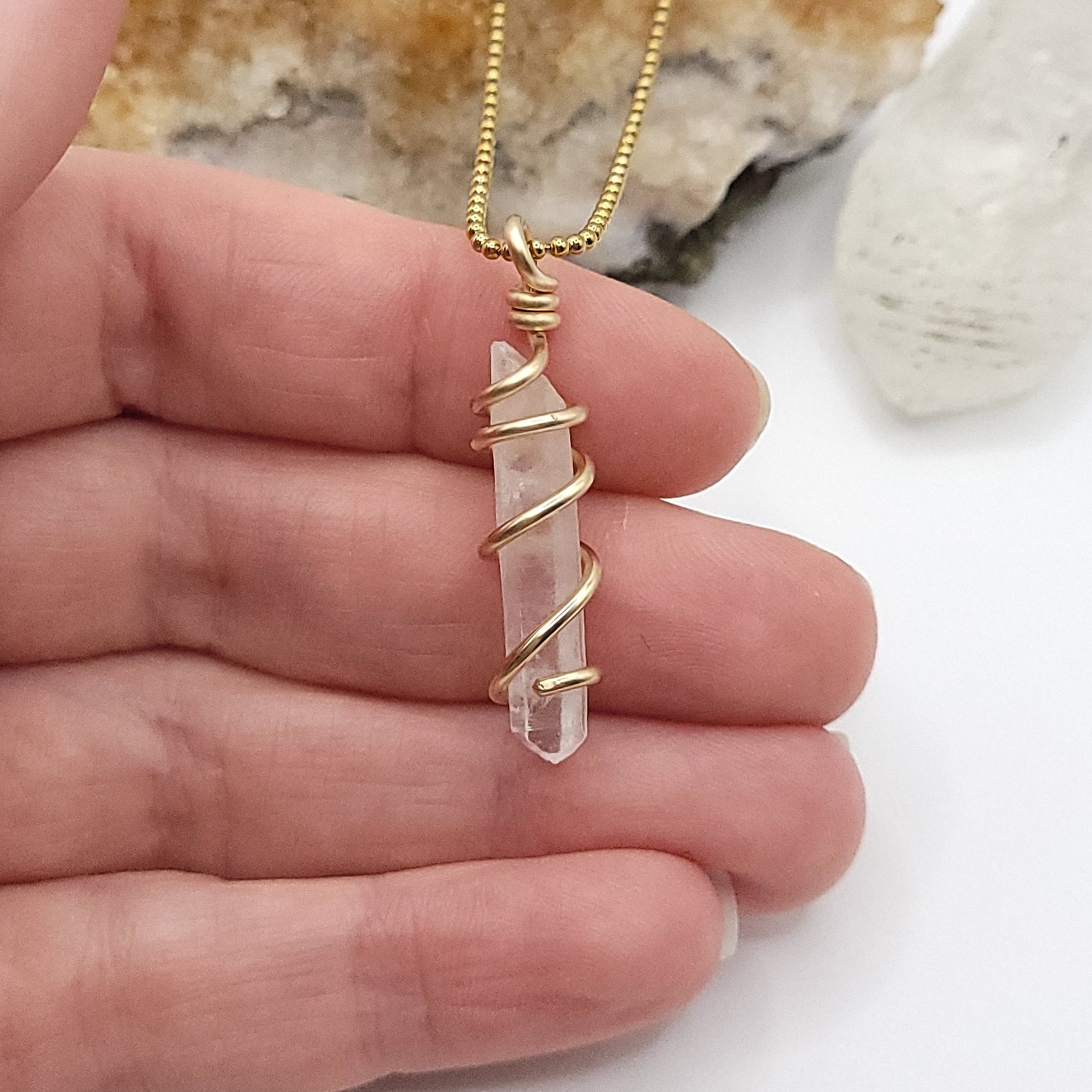 clear quartz necklace in gold wire in hand