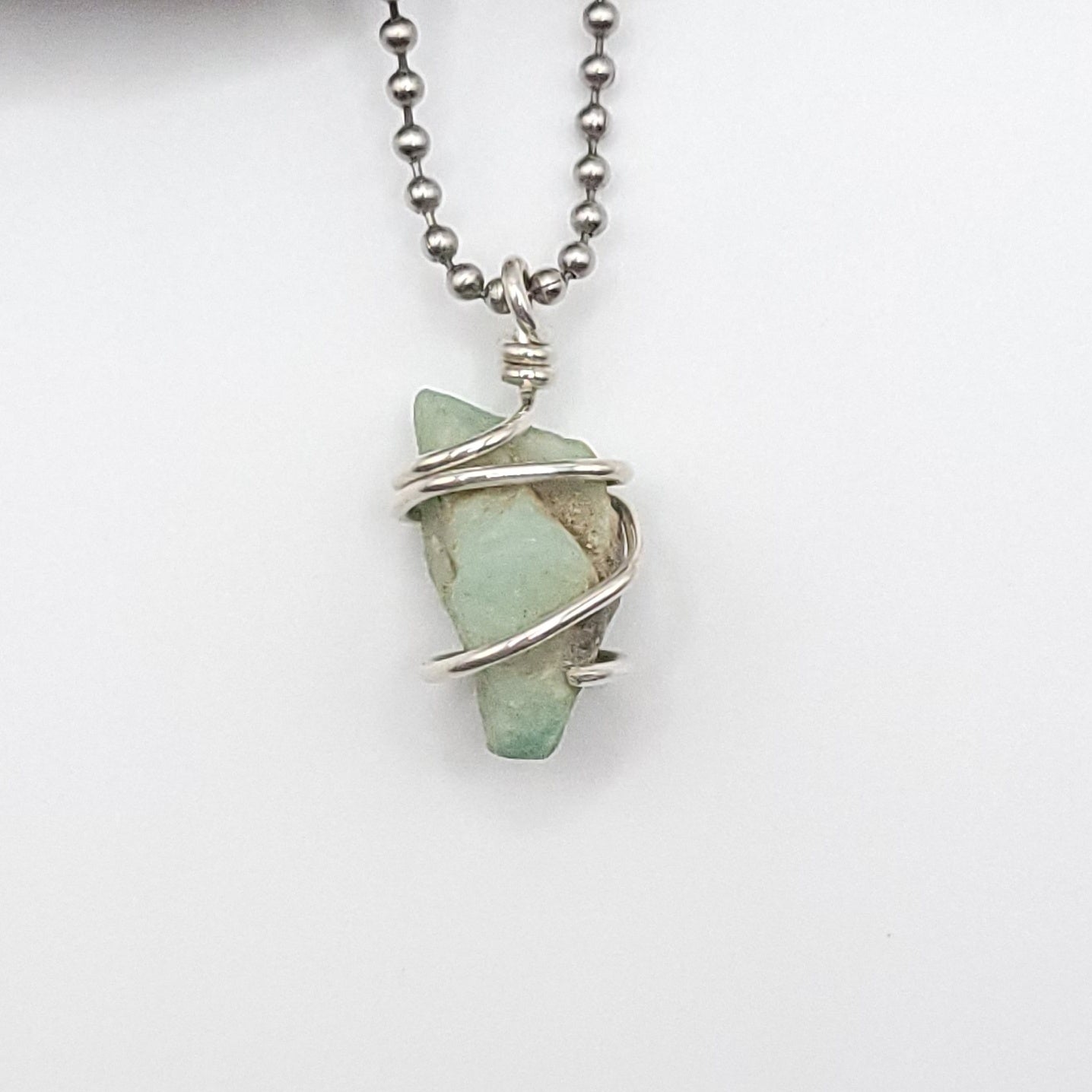 Raw Emerald necklace in silver wire wrap showcasing natural beauty and heart healing properties.