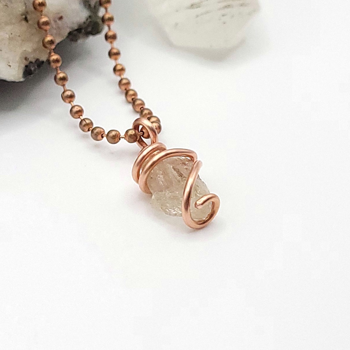 raw citrine in copper necklace on white background side view