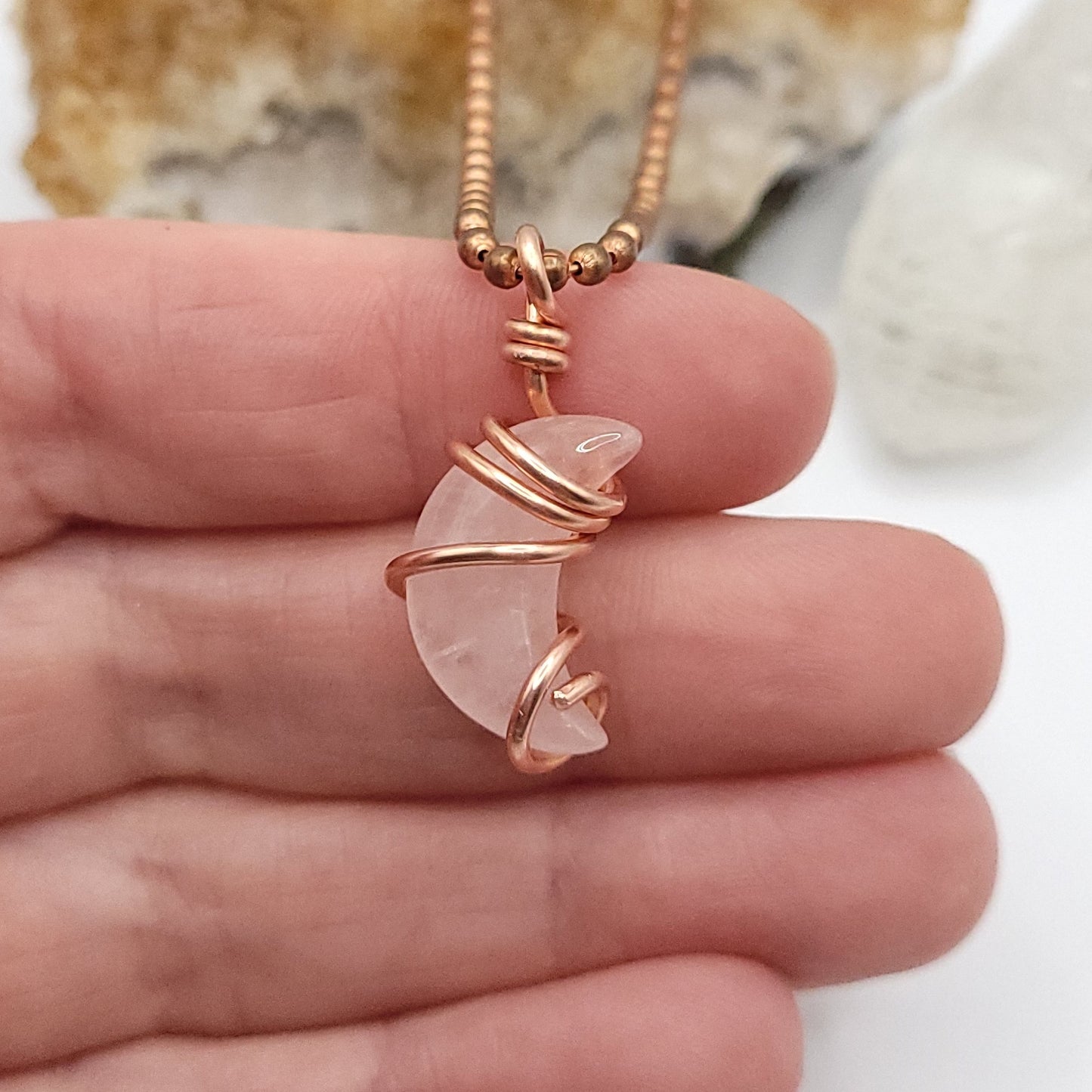 Rose quartz Crescent Moon crystal necklace in copper close up in hand