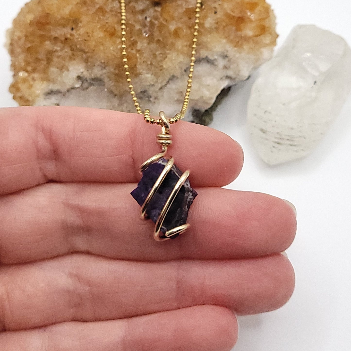 Raw Sugilite Crystal Necklace in Gold in hand
