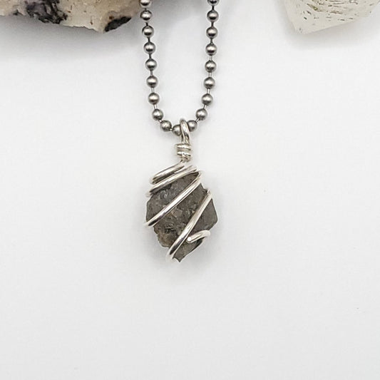 raw lazulite in silver wire on white background