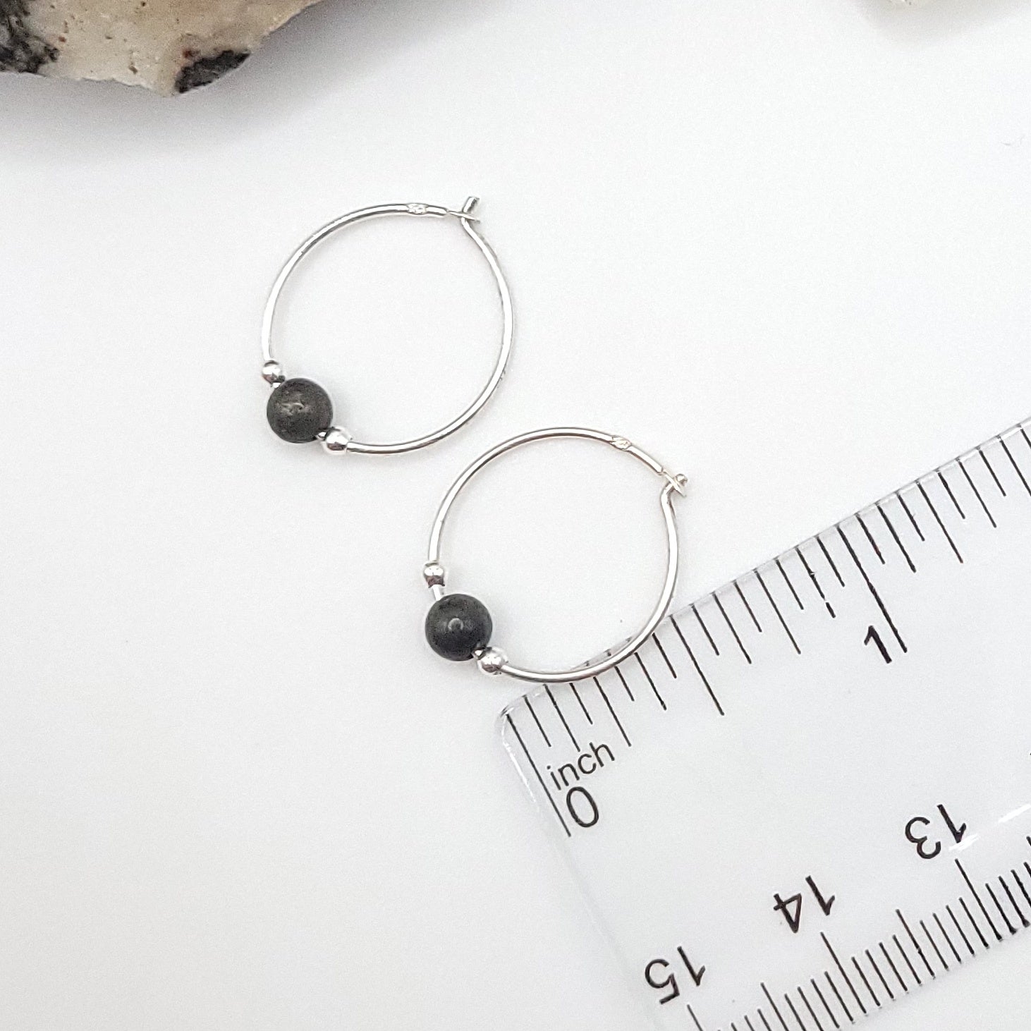 3/4' silver and pyrite hoops earrings next to a ruler