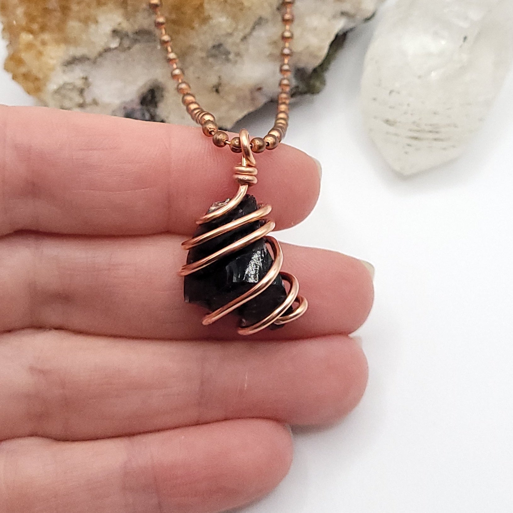 black obsidian necklace in copper on white background in hand