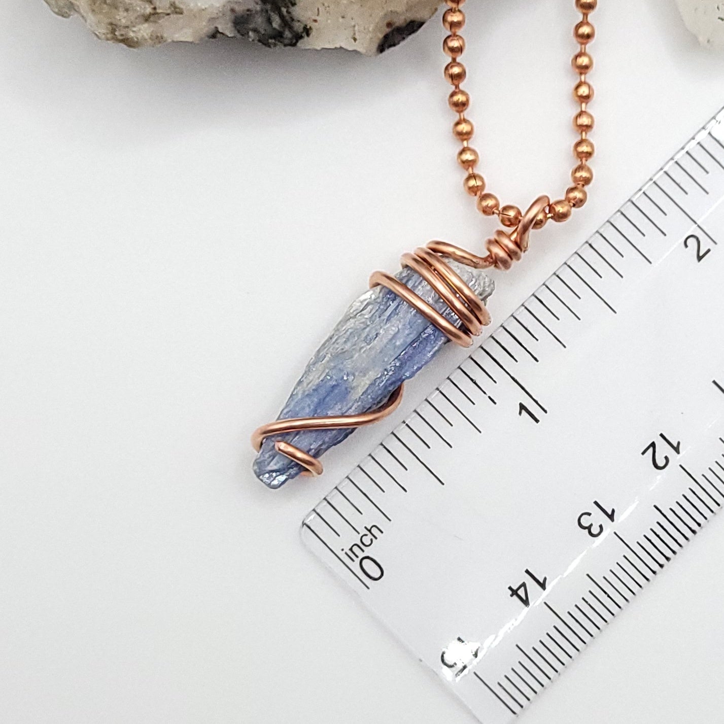 raw blue kyanite necklace in copper on white background next to ruler, measuring just over 1 inch
