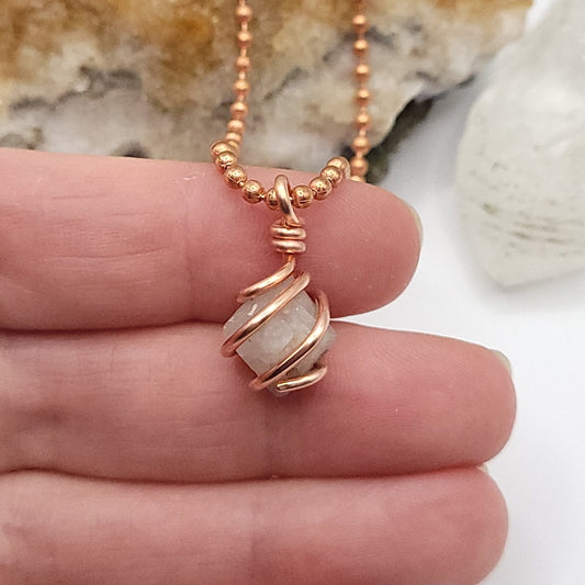 Hand holding a raw Beta Quartz necklace wrapped in copper, symbolizing transformation and clarity.