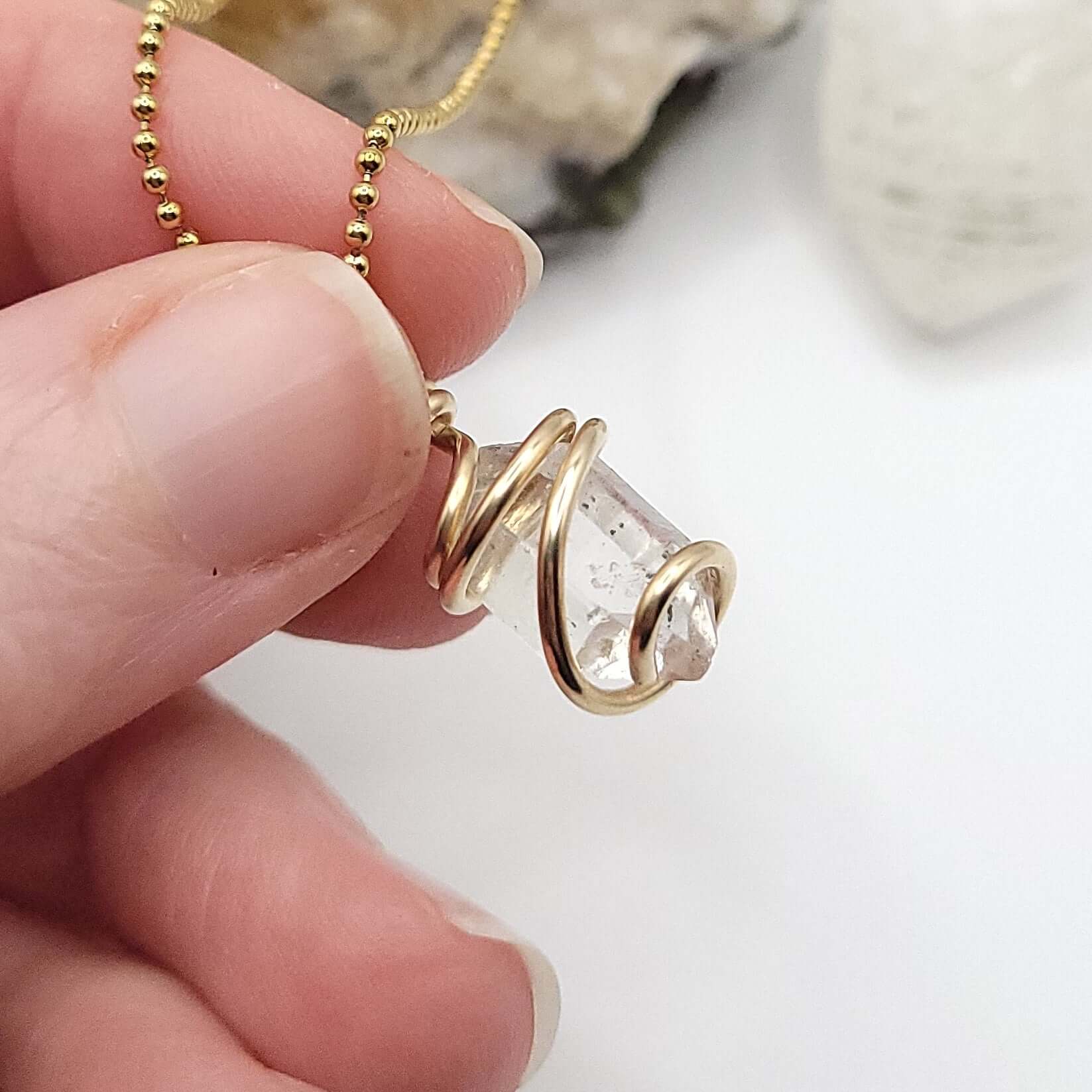 Herkimer diamond quartz necklace in gold side view over white background