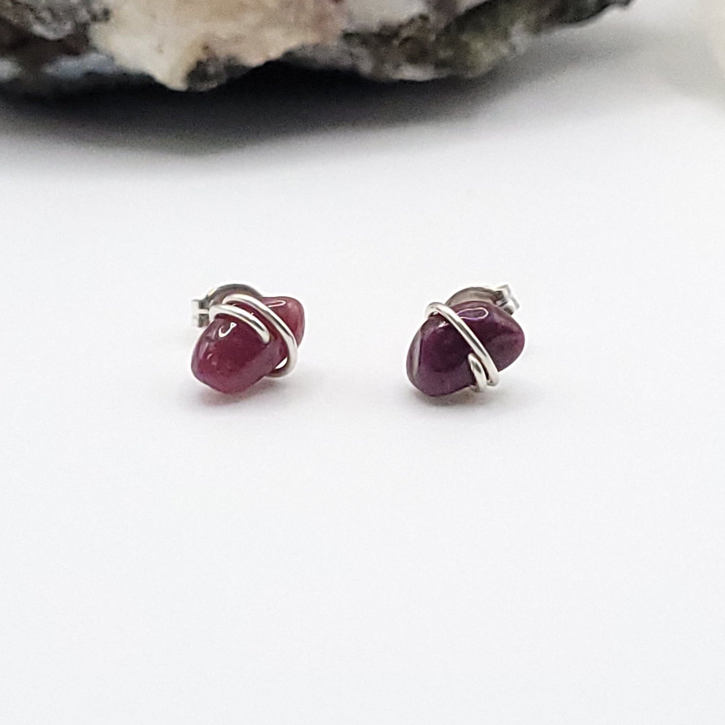 Pair of ruby stud earrings in silver on a white background