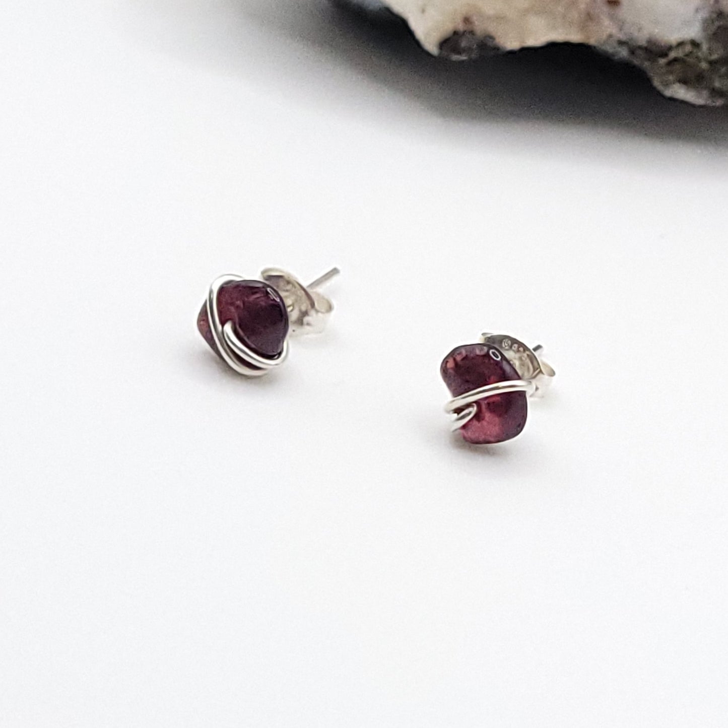 Pair of garnet gemstone stud earrings on a white background