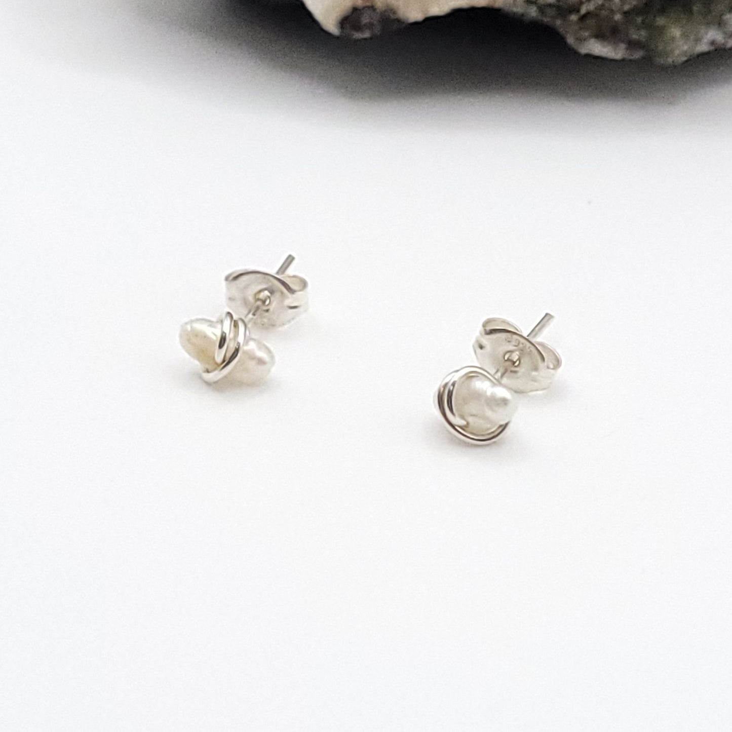 Pair of silver pearl stud earrings on a white background